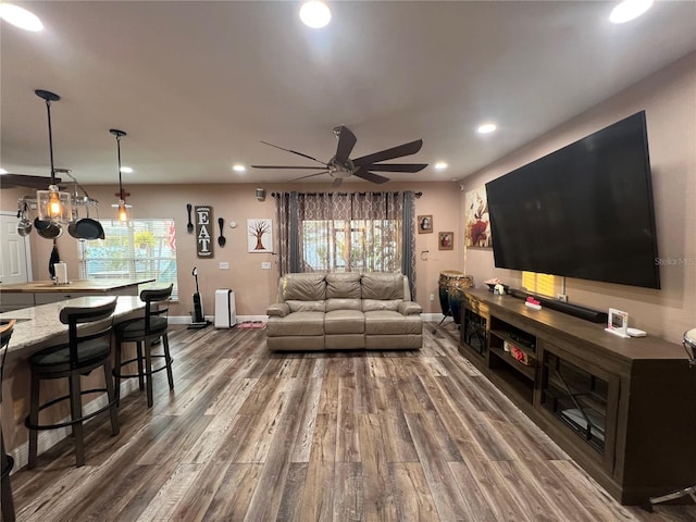 living room with dark wood-type flooring, ceiling fan, and a healthy amount of sunlight