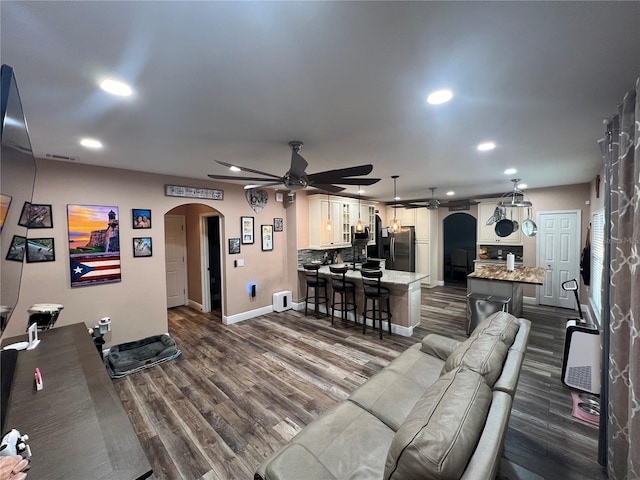 living room featuring ceiling fan and dark hardwood / wood-style floors