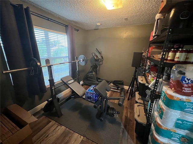 exercise area with hardwood / wood-style floors and a textured ceiling