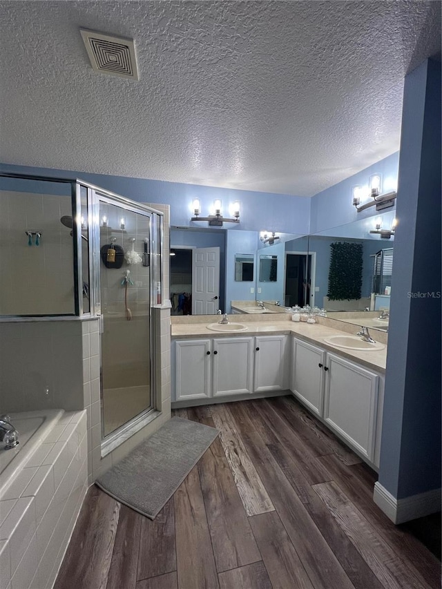 bathroom featuring plus walk in shower, hardwood / wood-style floors, vanity, and a textured ceiling