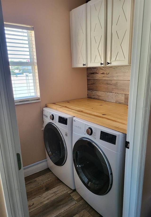 clothes washing area featuring cabinets, washing machine and dryer, plenty of natural light, and dark wood-type flooring