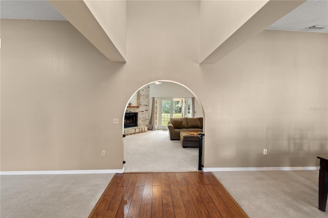 interior space with a towering ceiling, carpet floors, and a brick fireplace