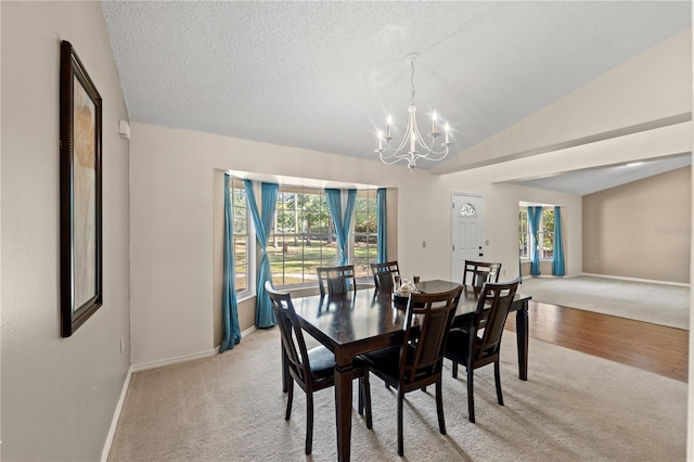 carpeted dining room featuring a textured ceiling, vaulted ceiling, and a chandelier