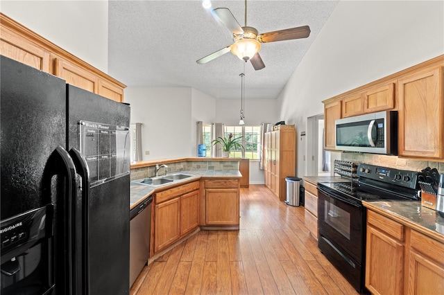 kitchen featuring sink, black appliances, a textured ceiling, decorative backsplash, and light wood-type flooring