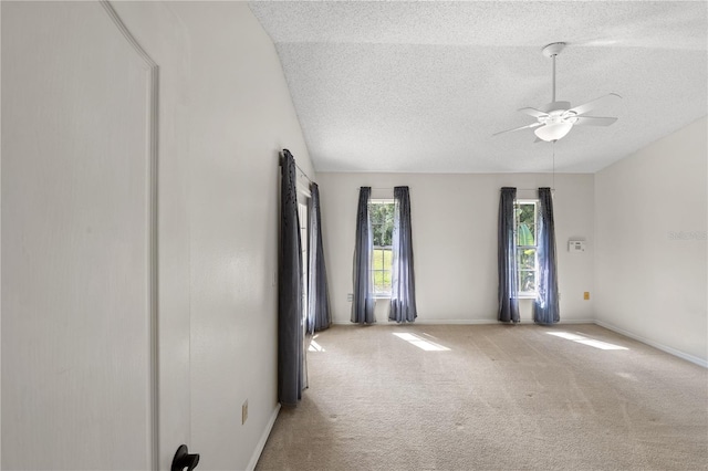 spare room featuring ceiling fan, lofted ceiling, carpet floors, and a textured ceiling