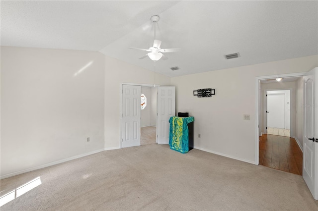 carpeted empty room with ceiling fan and vaulted ceiling