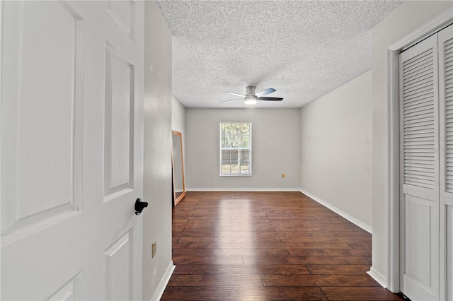 unfurnished bedroom with ceiling fan, dark hardwood / wood-style flooring, and a textured ceiling