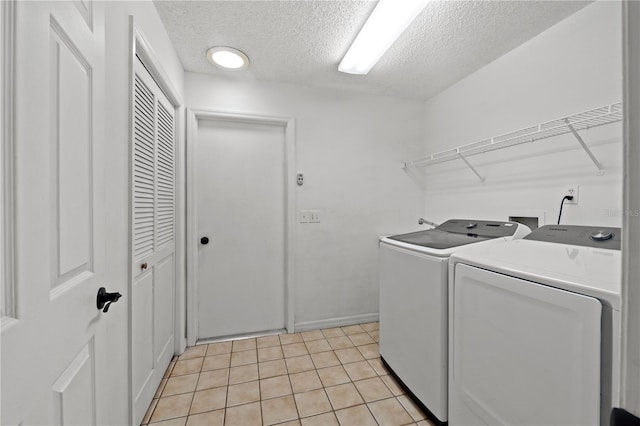 washroom featuring light tile patterned floors, a textured ceiling, and washer and clothes dryer