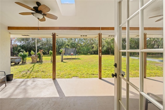 unfurnished sunroom featuring ceiling fan, a skylight, and a wealth of natural light