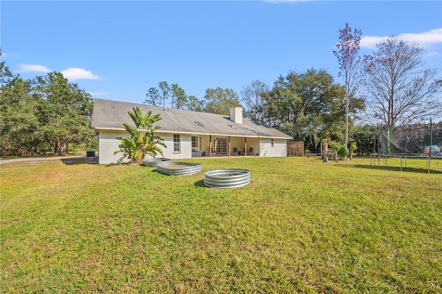 back of property with a trampoline and a lawn