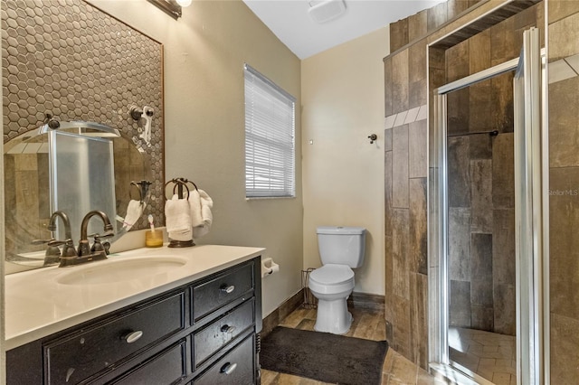 bathroom featuring a shower with door, vanity, and toilet