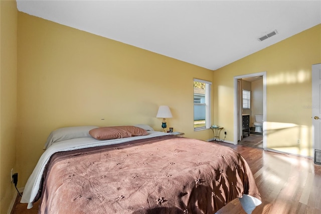 bedroom with vaulted ceiling, ensuite bath, and light hardwood / wood-style flooring