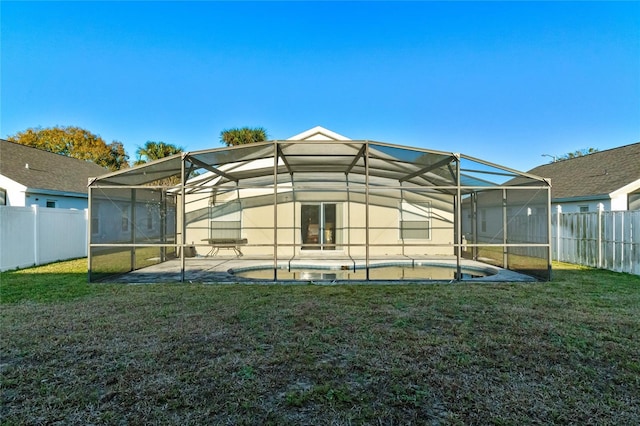 back of house featuring a lanai, a fenced in pool, a patio area, and a lawn