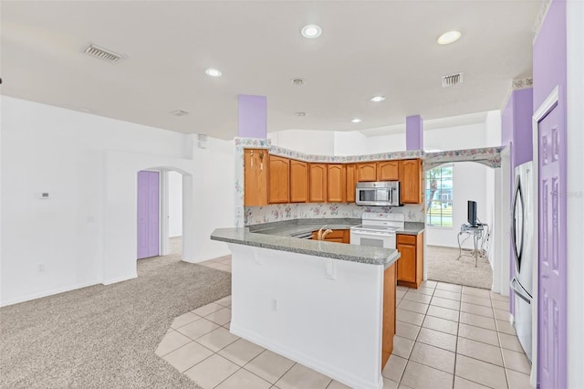 kitchen with stainless steel appliances, kitchen peninsula, and light carpet