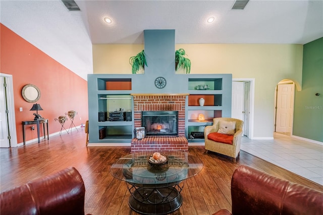 living room featuring a brick fireplace, hardwood / wood-style flooring, and built in features