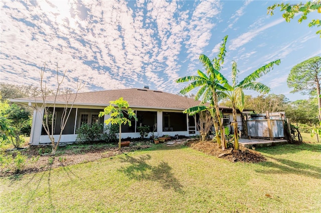 rear view of property featuring a sunroom and a yard