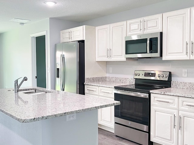 kitchen featuring stainless steel appliances, sink, a center island with sink, and white cabinets