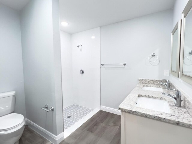 bathroom featuring vanity, hardwood / wood-style floors, toilet, and tiled shower