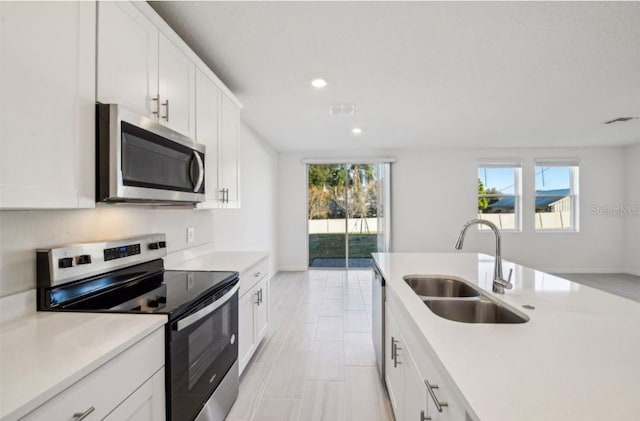 kitchen with stainless steel appliances, sink, a wealth of natural light, and white cabinets