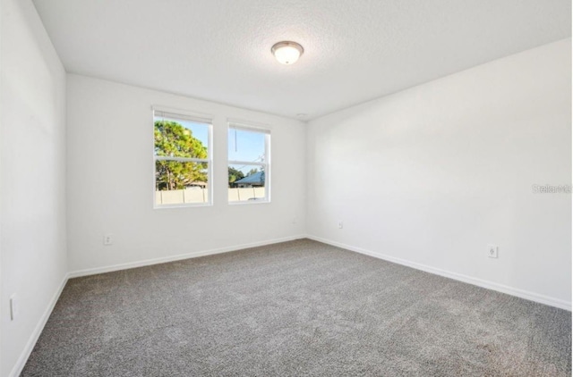 carpeted empty room with a textured ceiling