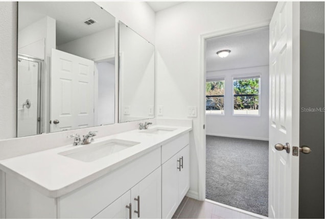 bathroom featuring vanity, an enclosed shower, and a textured ceiling