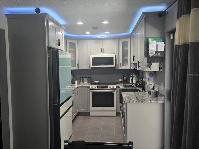 kitchen featuring white cabinetry, stainless steel range with electric stovetop, fridge, light stone countertops, and tile patterned floors