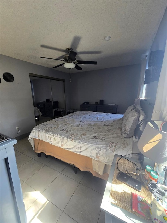 bedroom featuring a closet, ceiling fan, tile patterned flooring, and a textured ceiling