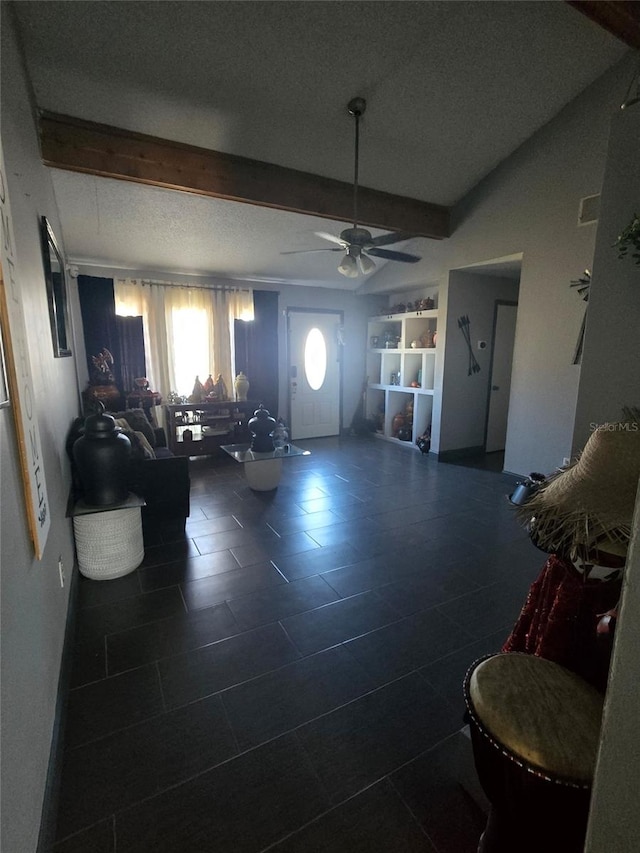 living room featuring beamed ceiling, ceiling fan, and a textured ceiling