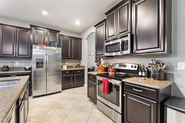 kitchen featuring dark brown cabinetry, light tile patterned floors, sink, and appliances with stainless steel finishes