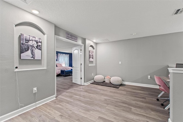 workout area featuring light hardwood / wood-style floors and a textured ceiling