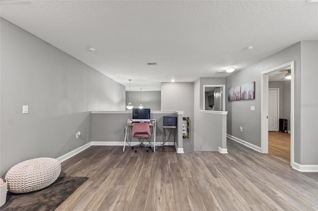 home office featuring wood-type flooring and a textured ceiling