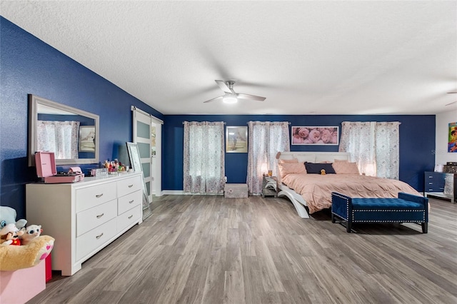 bedroom featuring multiple windows, ceiling fan, light hardwood / wood-style floors, and a textured ceiling