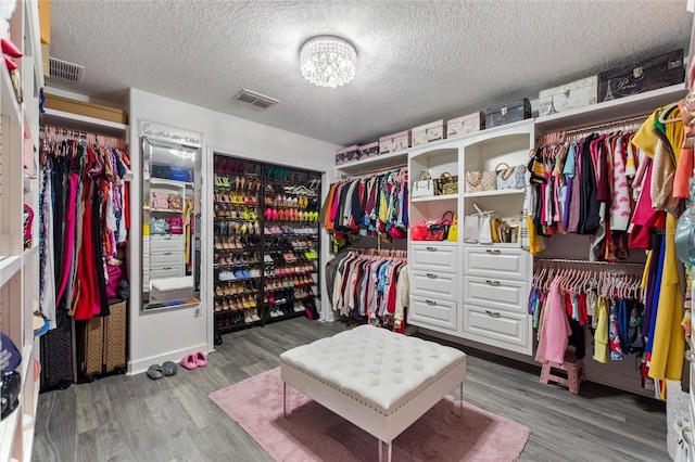 spacious closet featuring a notable chandelier and hardwood / wood-style flooring