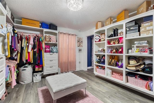 walk in closet featuring hardwood / wood-style flooring and an inviting chandelier