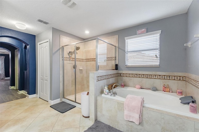 bathroom featuring tile patterned flooring, shower with separate bathtub, and a textured ceiling