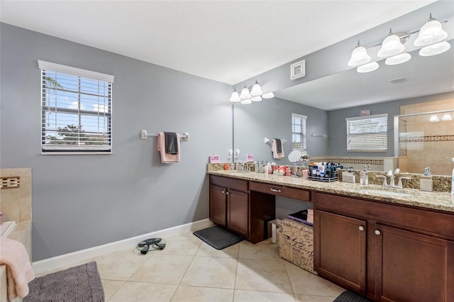 bathroom with vanity, tile patterned floors, a healthy amount of sunlight, and a tile shower