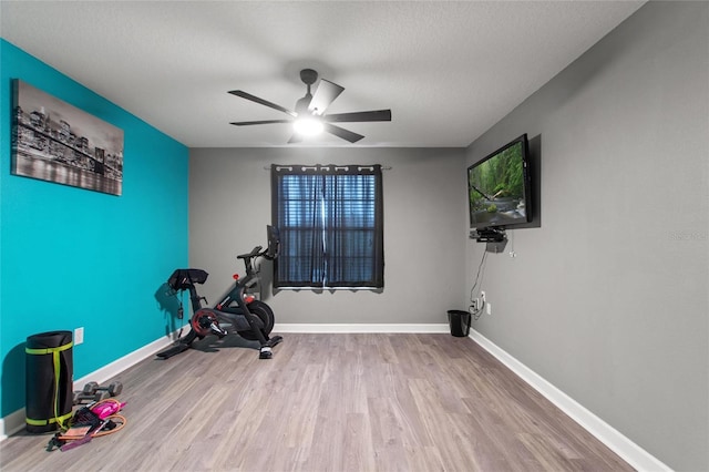 workout room with ceiling fan, light hardwood / wood-style flooring, and a textured ceiling