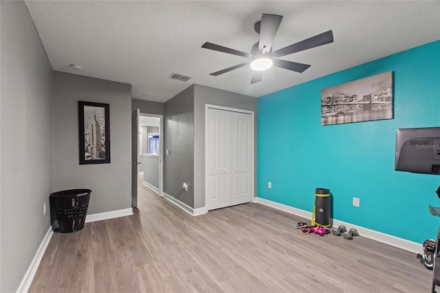 interior space with ceiling fan, a textured ceiling, and light hardwood / wood-style flooring