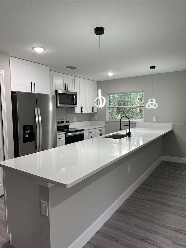 kitchen featuring stainless steel appliances, hanging light fixtures, and white cabinets