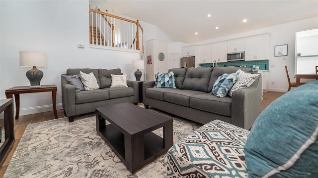 living room featuring lofted ceiling, sink, and light hardwood / wood-style flooring