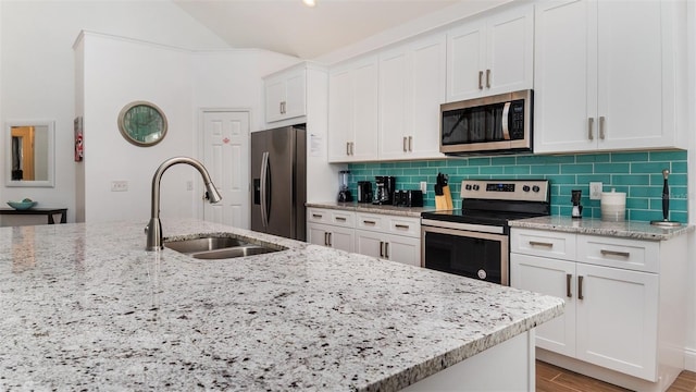 kitchen with appliances with stainless steel finishes, sink, white cabinets, decorative backsplash, and light stone countertops