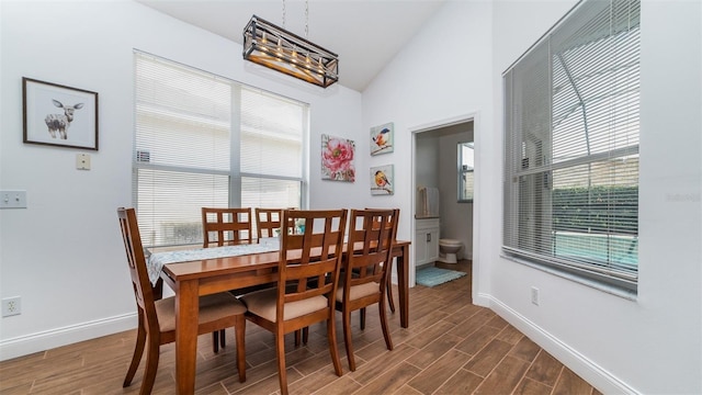 dining space with an inviting chandelier, dark wood-type flooring, vaulted ceiling, and plenty of natural light