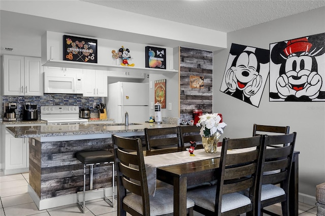 interior space with light stone counters, white appliances, a textured ceiling, and white cabinets