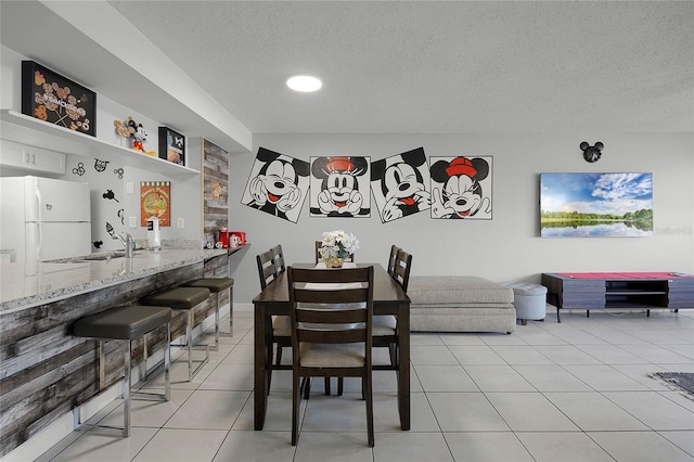 tiled dining space featuring sink and a textured ceiling