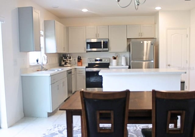 kitchen with appliances with stainless steel finishes, sink, light tile patterned floors, and white cabinets