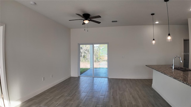 unfurnished living room featuring ceiling fan, dark hardwood / wood-style flooring, and sink