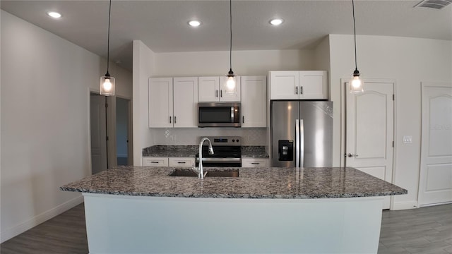 kitchen featuring white cabinetry, hanging light fixtures, an island with sink, and appliances with stainless steel finishes