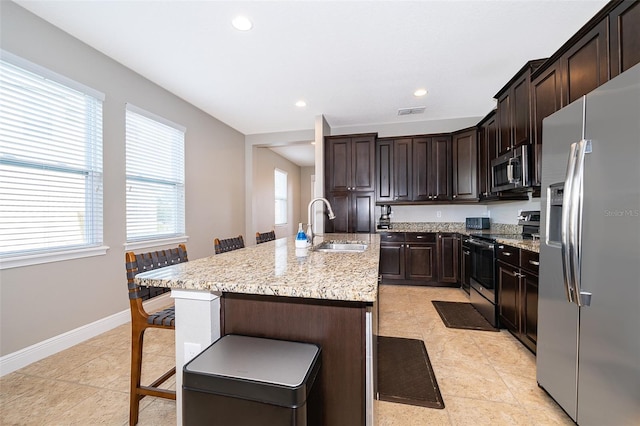 kitchen featuring appliances with stainless steel finishes, a kitchen breakfast bar, a kitchen island with sink, and light tile patterned floors