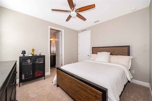 bedroom with connected bathroom, light colored carpet, and ceiling fan