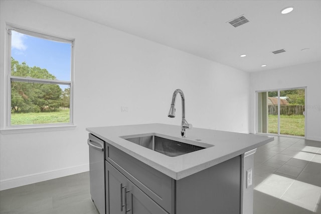 kitchen featuring sink, gray cabinets, an island with sink, and dishwasher